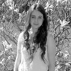 Autorin Yvonne Singer im Portait und lächelt in die Kamera vor einem Blumenbusch