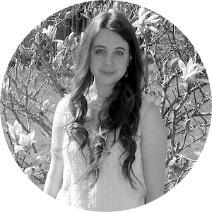 Autorin Yvonne Singer im Portait und lächelt in die Kamera vor einem Blumenbusch