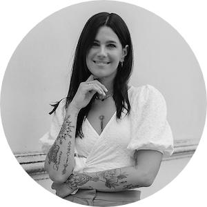 Autorin Nina Wirths schaut lächelnd und mit verschränkten Armen in die Kamera